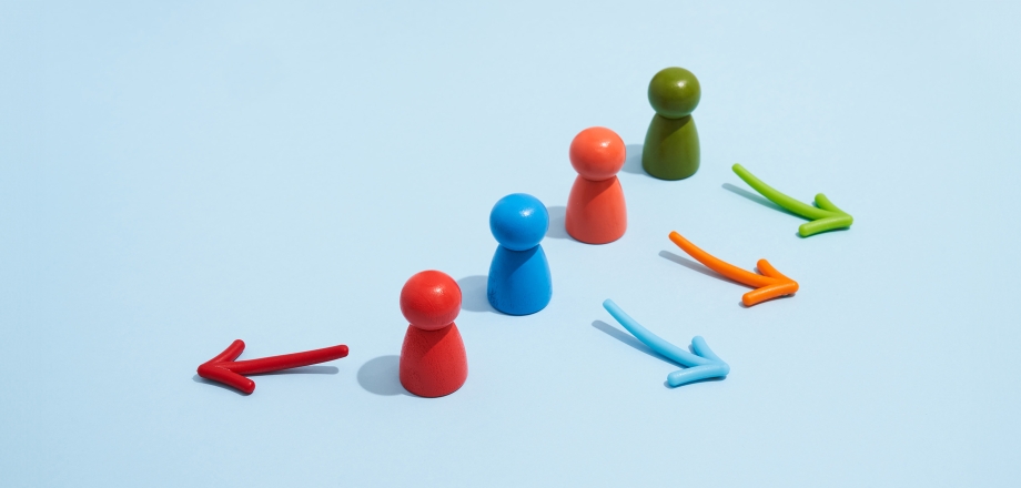 Red, blue, orange, and green wooden game pieces with arrow next to each