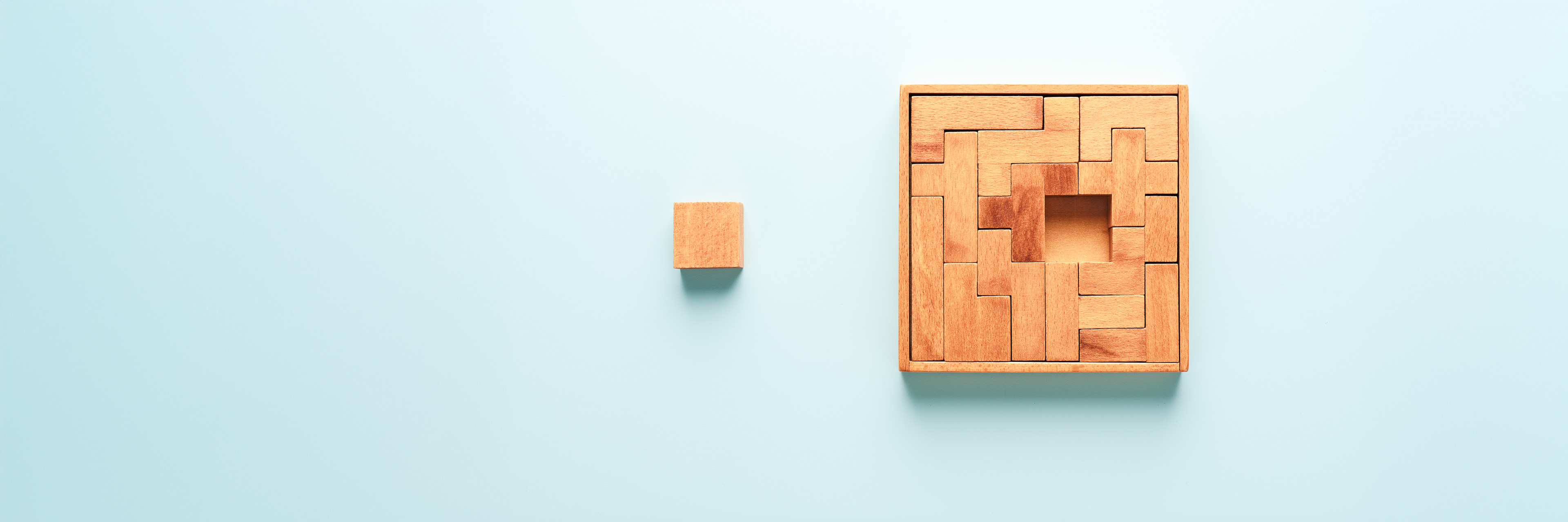 Wooden Puzzle with a Missing Piece on Light Blue Colored Background.