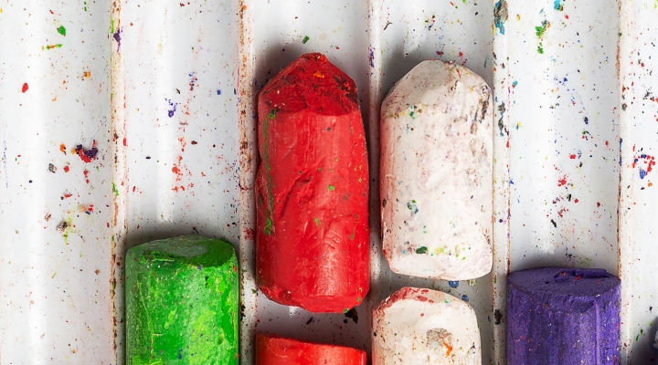 An image of different colors of chalk in a tray.