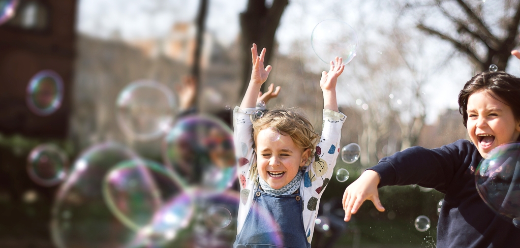 Small children having fun playing with bubbles, a reminder of what's most important about investing.