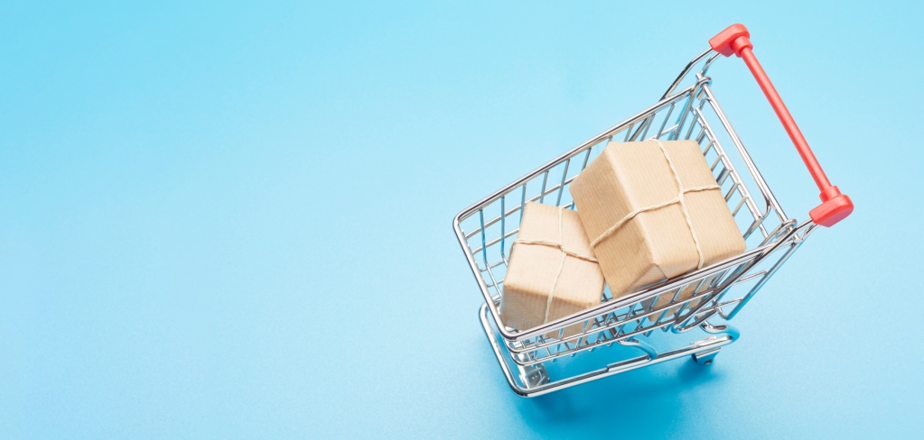 A shopping cart containing boxes seen from above on a bright blue background.