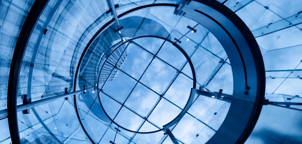 A dramatic blue glass structure forms part of an office building 