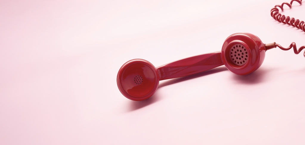 A red phone on a light pink background.