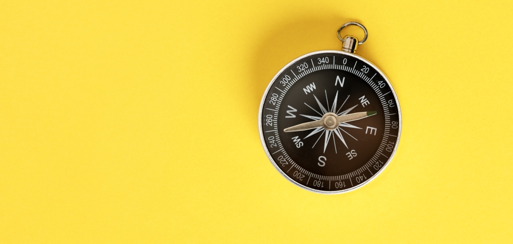 A compass on a bright yellow background.