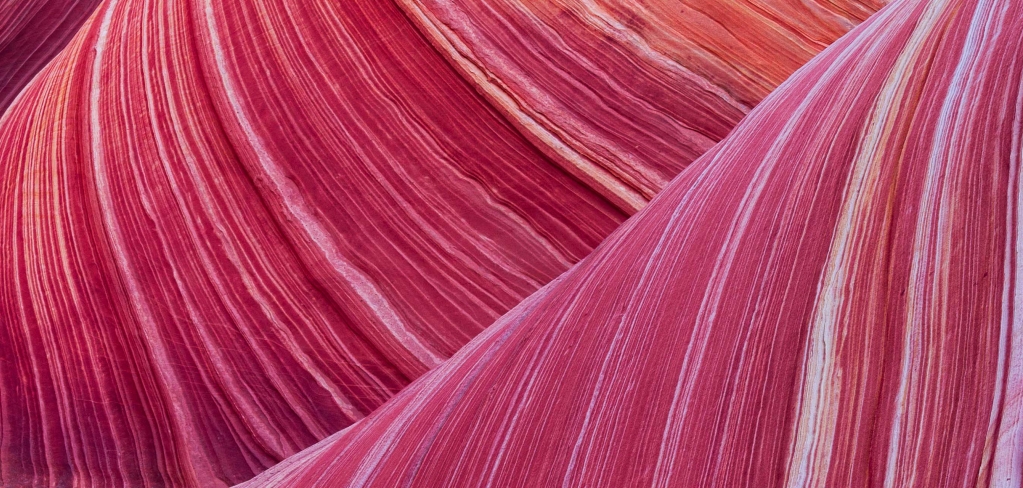 Close up of rocks where you can see a wavy texture with various shades of red.