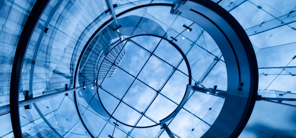 A dramatic blue glass structure forms part of an office building 